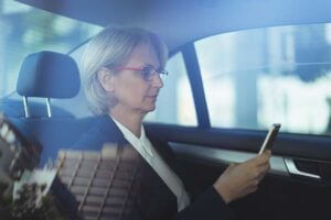 Female business traveller checking her phone a taxi