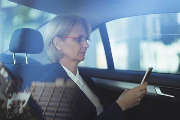 Female business traveller checking her phone a taxi