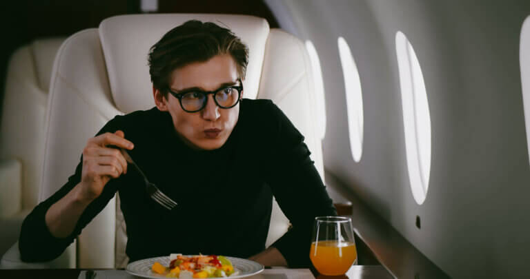 Handsome young businessman eating salad in private jet - Midas Travel Management - Midas Travel Management Recycling tips for business travellers