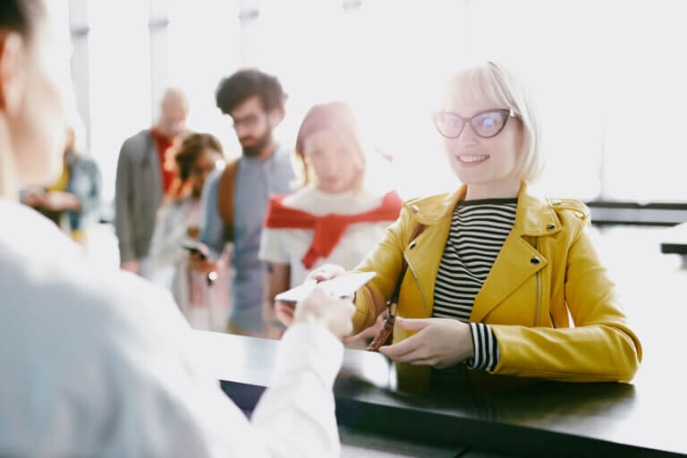 Woman giving ID on check in - Midas Travel Management - Midas Travel Management REAL ID will be required for domestic US flights