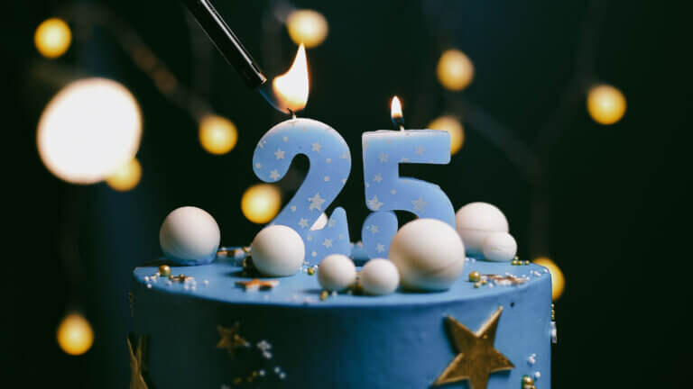 Birthday cake number 25 stars sky and moon concept blue candle is fire by lighter Copy space on right side of screen Close-up - Midas Travel Management - Midas Travel Management MIDAS Travel is 25!